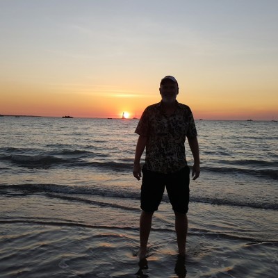 Robert with feet planted in the sea at sunset at Mindil Beach, Darwin